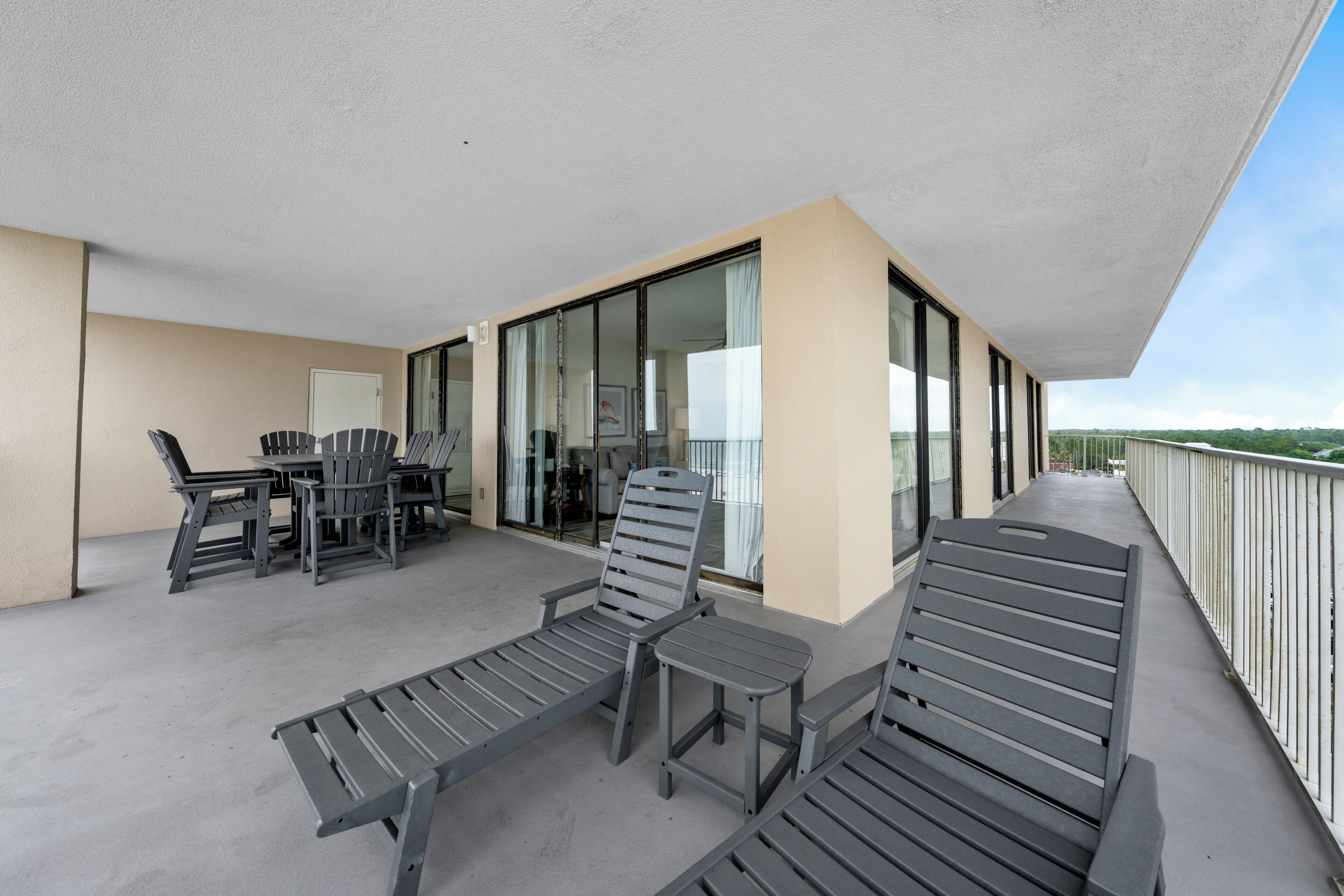A balcony with lounge chairs, a table, and chairs.