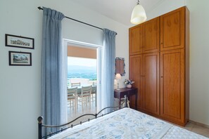 A bedroom with a bed, a wooden wardrobe, a desk with a lamp, and a view through a door. - Villa Aeolos – Private Swim Spa, Sea View, Wi-Fi, Air Conditioning (Vigla)