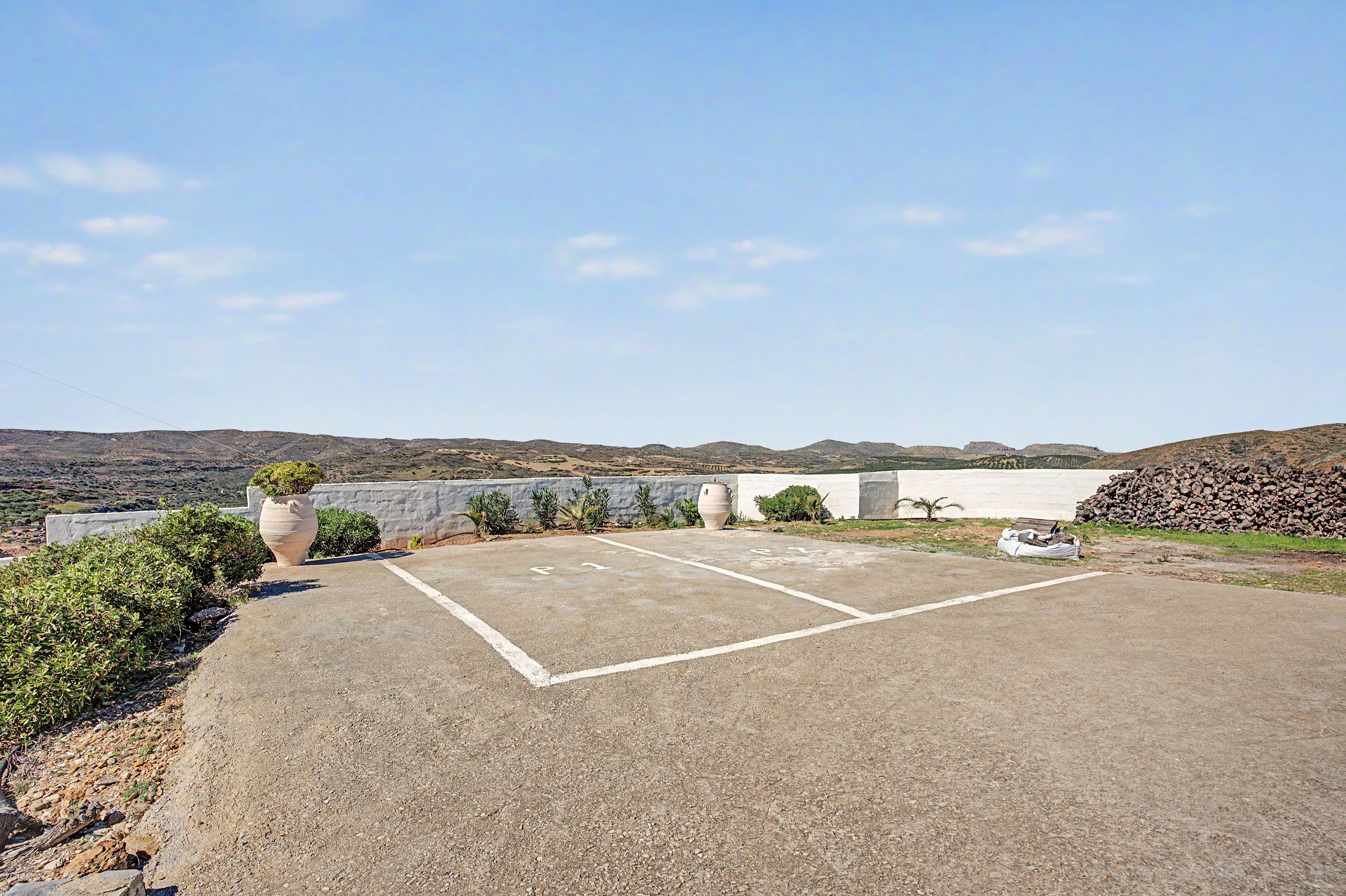 A parking area with a clear view of the surrounding landscape, including hills and a distant body of water.