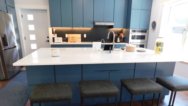 A modern kitchen with a central island, bar stools, and built-in appliances. - Brand new GORGEOUS contemporary home (CS0054) (Wellfleet)