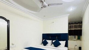 A bedroom with a bed, a ceiling fan, and a window with curtains. - Hotel RS International (New Delhi)