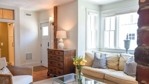 Een woonkamer met een glazen salontafel, een bank, een houten dressoir en een lamp.