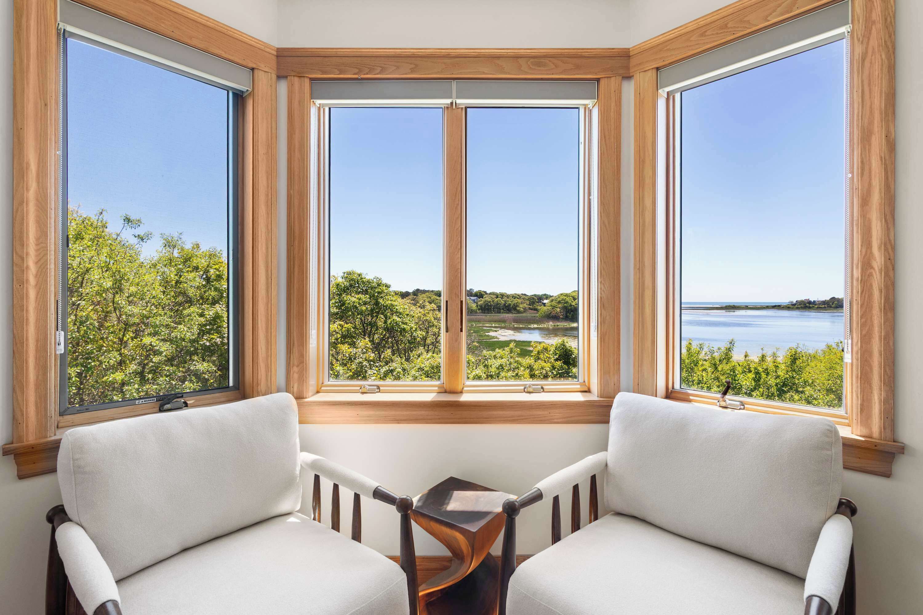 A corner room with a large bay window overlooking a lake and greenery.