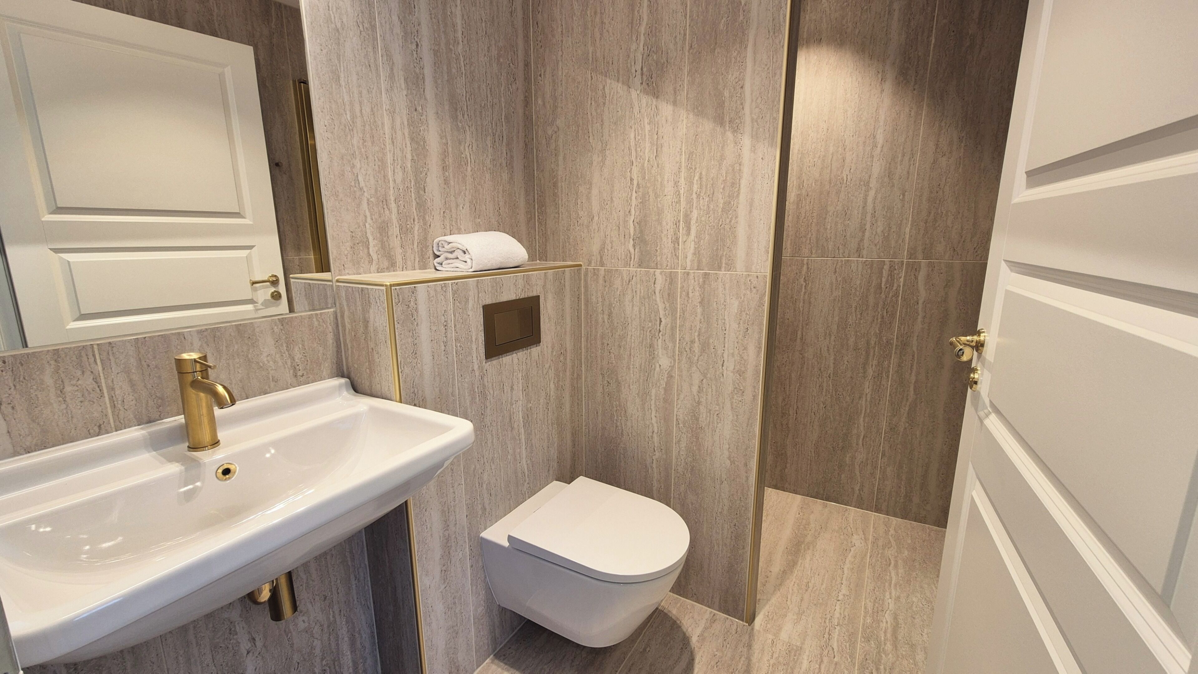 Un bagno con un lavandino bianco, un rubinetto dorato e un water.