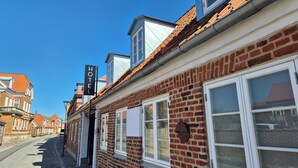 A hotel with a brick facade, large windows, and a clear blue sky. - Jacobs Hotel (Ringkøbing)
