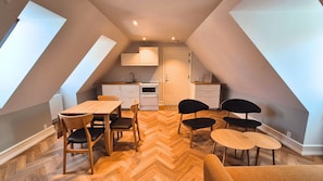 Un apartamento pequeño y moderno con cocina, comedor y habitación doble tipo altillo.
