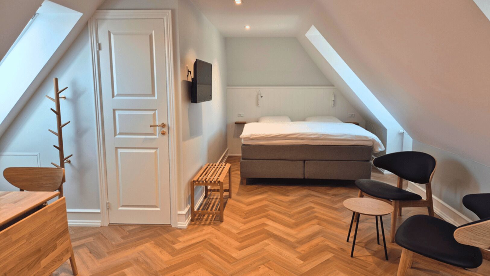 Un dormitorio con cama, televisor, banca de madera y una silla.