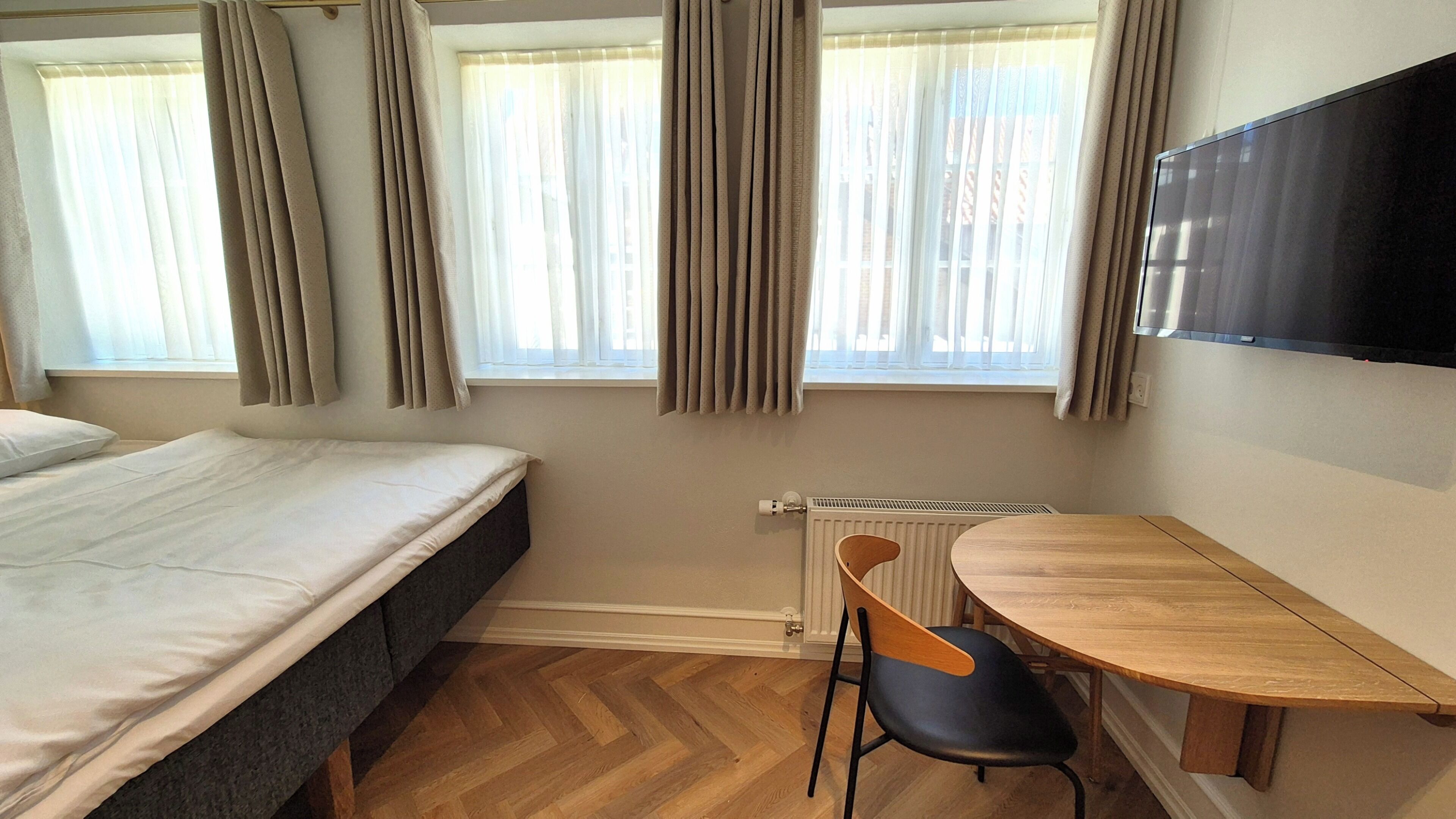 Un dormitorio con cama, escritorio, silla y radiador.