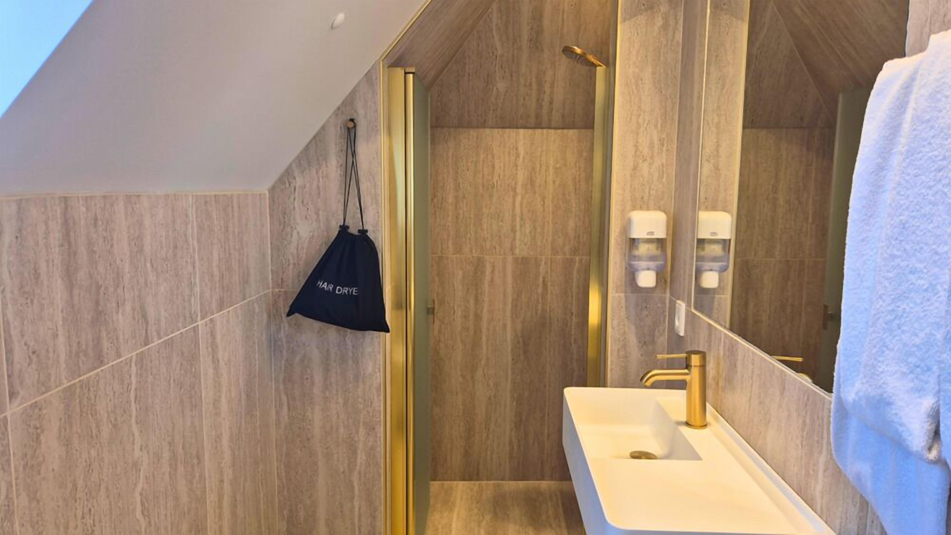 A modern bathroom with a large mirror, a white sink, and a shower area.