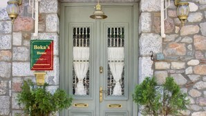 Un edificio in pietra con una porta verde doppia, due vasi con piante e un cartello con scritto Boka's House.
