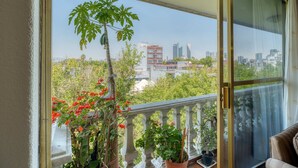 Un balcón con plantas en macetas y vista a un paisaje urbano.