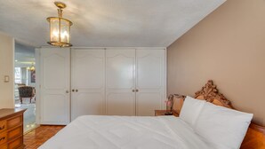 Un dormitorio con una cama grande, un aparador de madera, una mesita de noche y un armario.