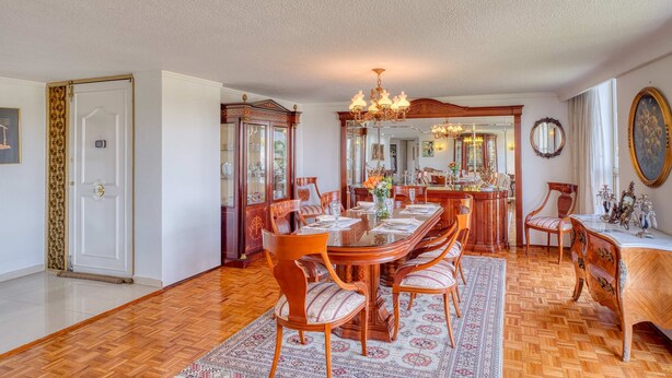 Comedor con una gran mesa de madera, sillas y un candelabro.