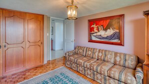 Una habitación con un armario de madera, un sofá estampado, un cuadro en la pared y una alfombra con diseño.