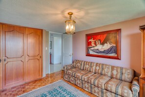 Ein Zimmer mit einem Holzschrank, einem gemusterten Sofa, einem Bild an der Wand und einem Teppich mit Muster.