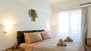 A bedroom with a bed, nightstands, a wall art piece, and a window with curtains. - Sinani Beachfront Gems Rhodes Jacuzzi Haven (Rhodes)