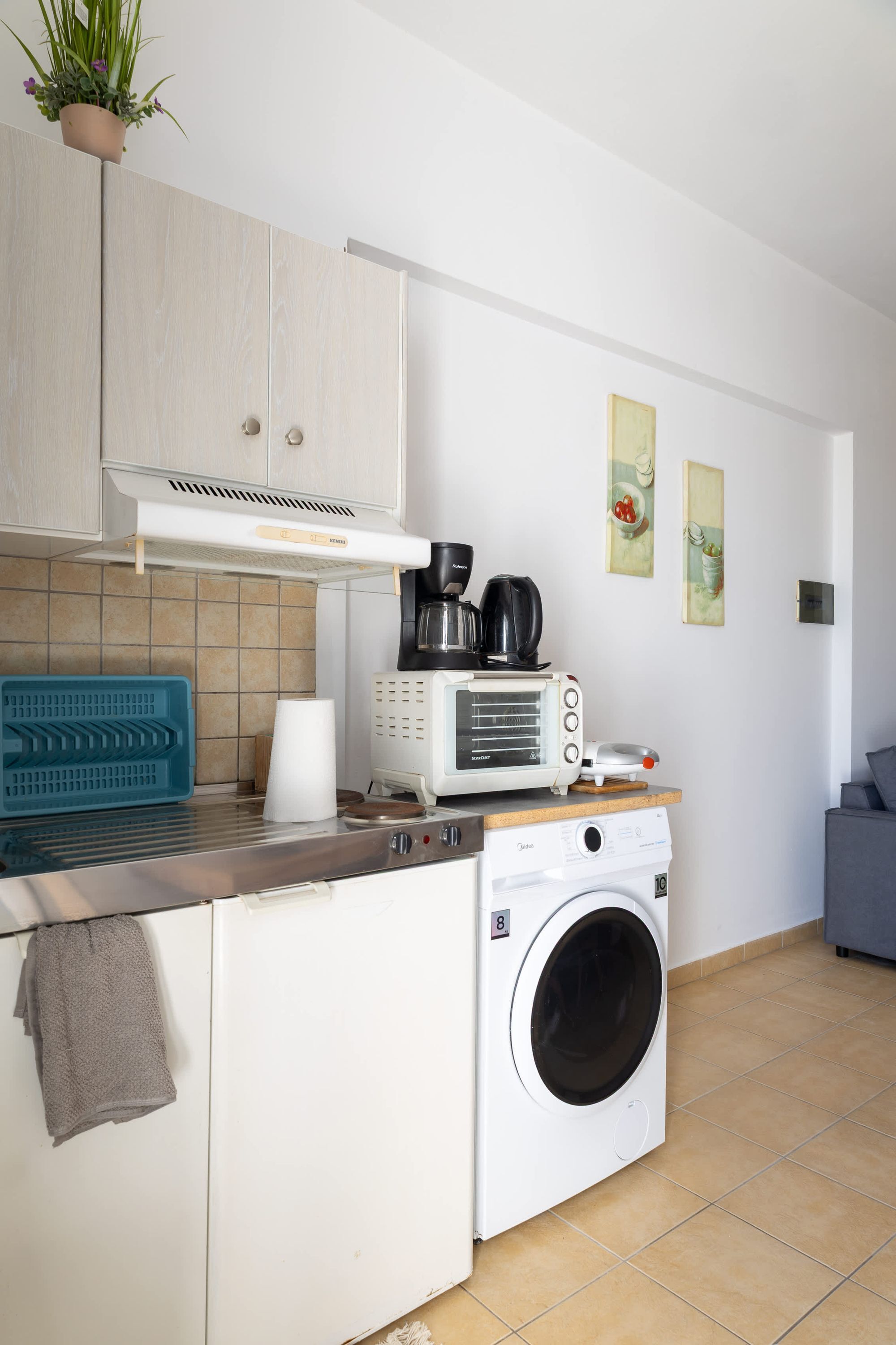 A compact kitchen with a washing machine, a microwave, and a coffee maker.