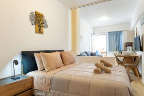 Ein Hotelzimmer mit Bett, Schreibtisch, Stuhl, Nachttisch, Lampe und einem Bild an der Wand.