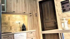 A kitchen with wooden cabinets, a dishwasher, a ceiling fan, and a dark wooden door. - Private Beachfront House Irene Mare Vagionia Bay (Poros)