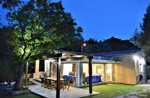 A modern house with a covered patio, a dining area, and a well-maintained lawn. - Private Beachfront House Irene Mare Vagionia Bay (Poros)