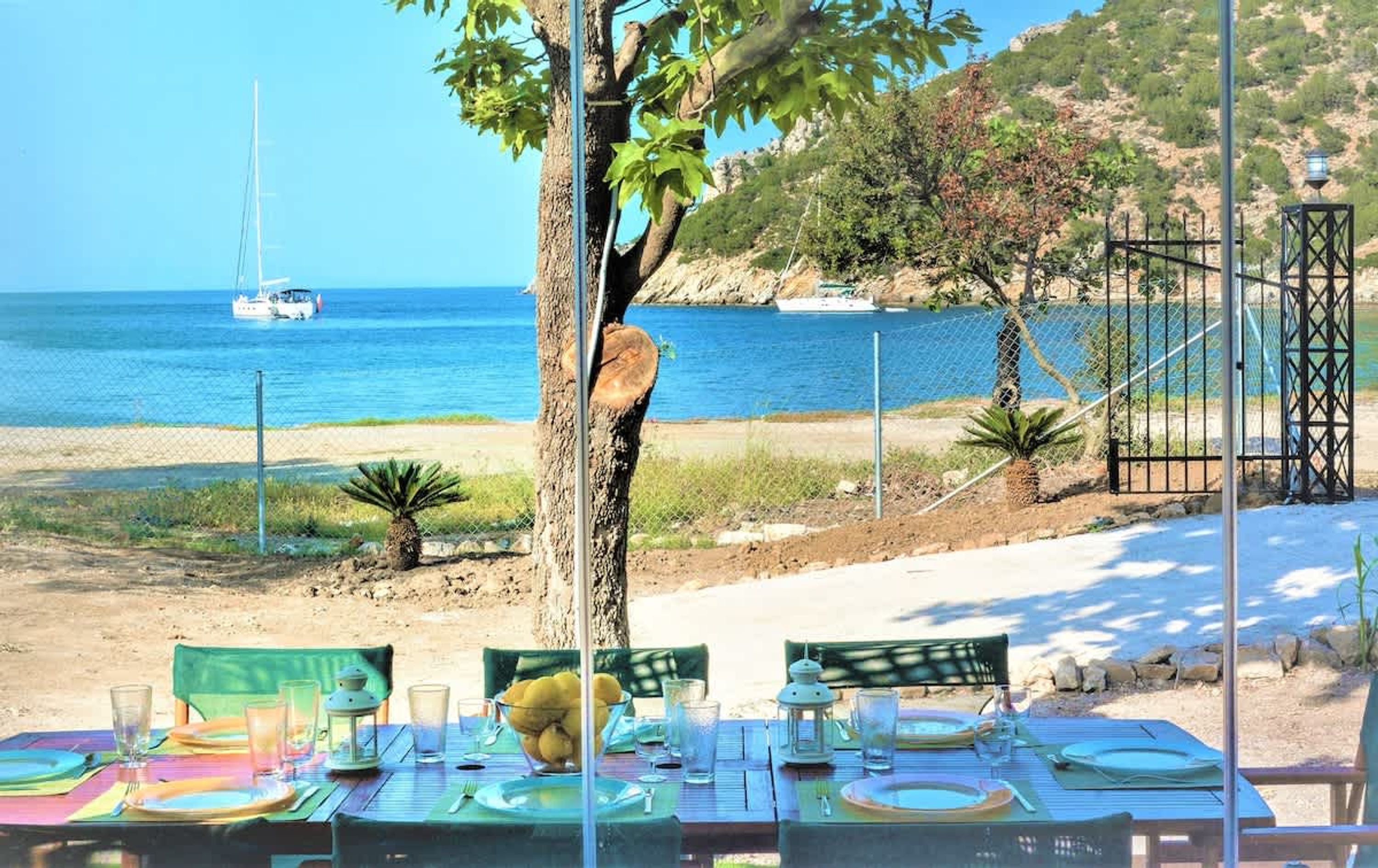 Mesa lista para comer con vista al mar y barcos.