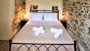 A bedroom with a bed, wooden ceiling, stone walls, and a ceiling fan. - Private Beachfront House Irene Mare Vagionia Bay (Poros)