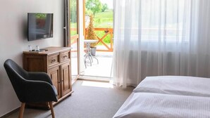A hotel room with a bed, a TV, a wooden cabinet, a chair, and a balcony with a table and chairs. - Chalet Mountain View Nova Lesna (Nová Lesná)