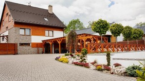 A two-story house with a stone facade, wooden exterior, and a paved driveway. - Chalet Mountain View Nova Lesna (Nová Lesná)