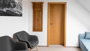 A room with a wooden door, two grey chairs, a blue sofa, and a framed picture on the wall. - Chalet Mountain View Nova Lesna (Nová Lesná)