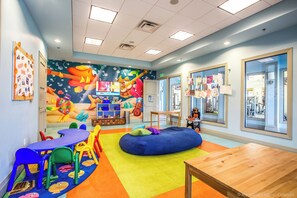 A brightly colored children's playroom with a large mural, colorful furniture, and a wooden table.