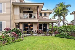 Ein zweistöckiges Haus mit Balkon, Terrasse und Gartenmöbeln sowie ein gepflegter Garten.