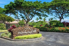 Schild für Waikoloa Beach Villas auf Steinsockel, umgeben von üppiger Vegetation und Bäumen.
