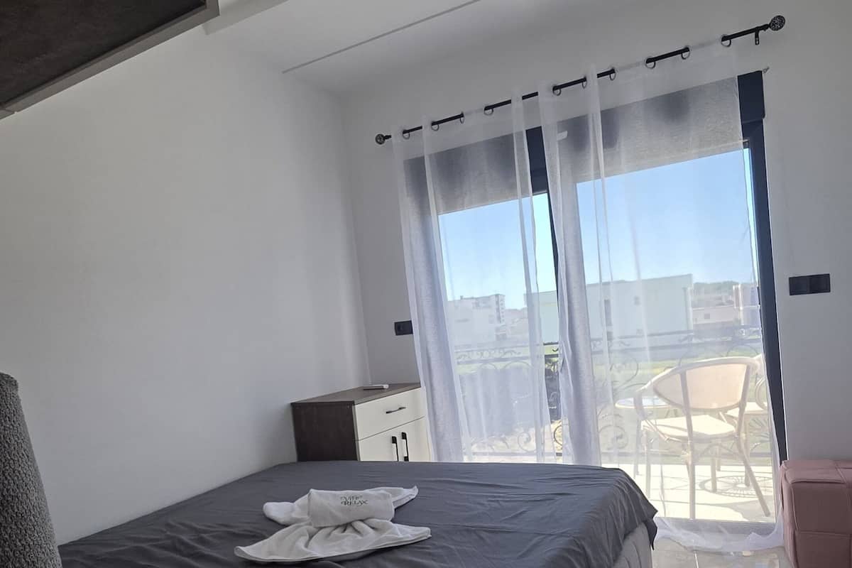 Une chambre moderne avec un grand lit, une table de chevet, une chaise et un balcon avec vue.