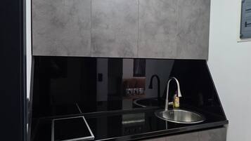 Eine moderne Küche mit schwarzem Arbeitsplatz, grauen Schränken, einer Edelstahl-Spüle und einem eingebauten Backofen.