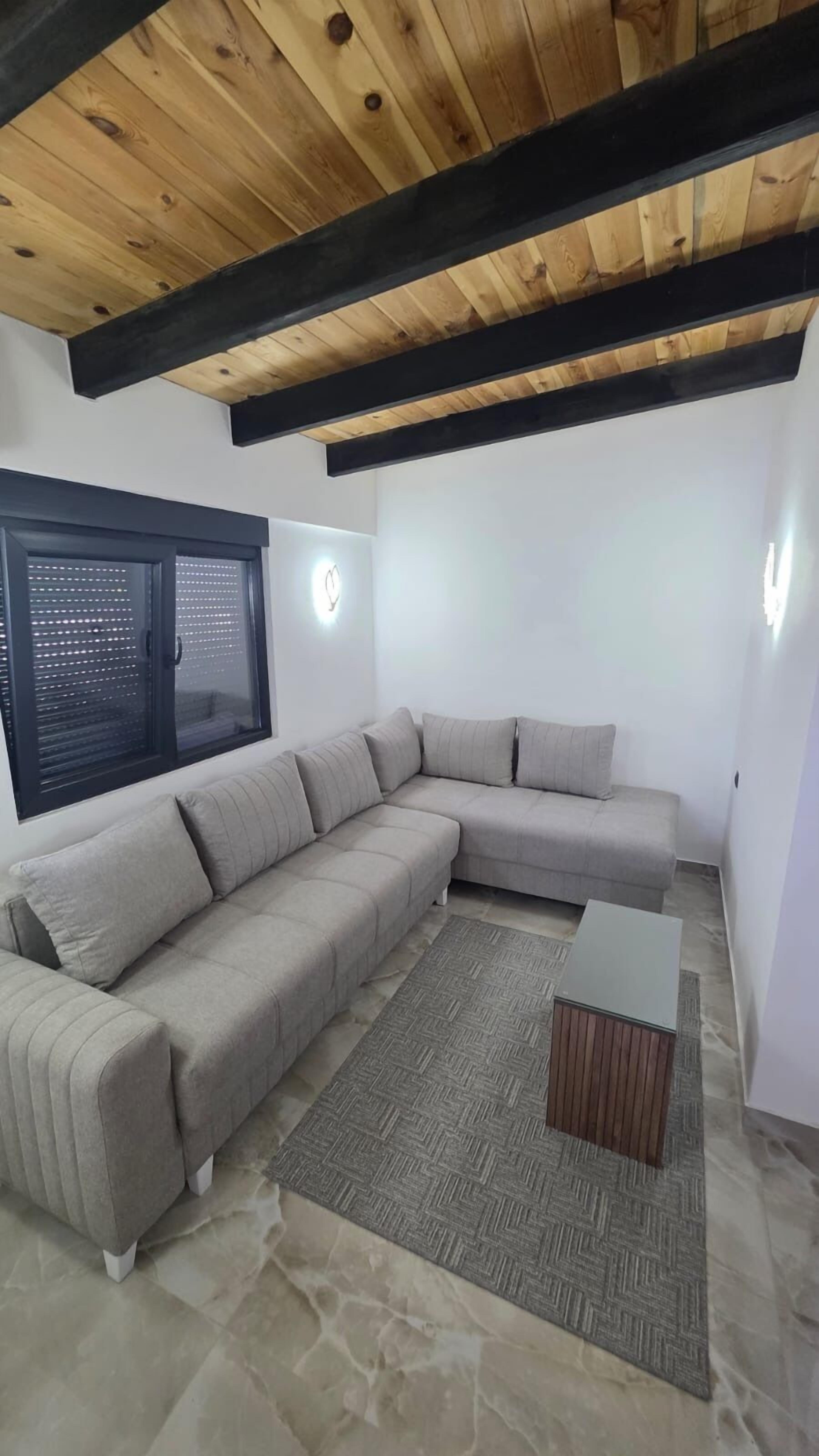 Een moderne woonkamer met een modulaire bank, een bijzettafeltje en een kamerbreed tapijt.