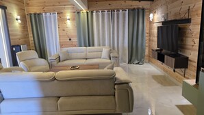 A modern living room with a sofa, armchairs, a coffee table, and a television mounted on a wooden wall. - Vile Relax (Ulcinj)