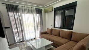 A living room with a sectional sofa, a coffee table, and a large window with curtains. - Vile Relax (Ulcinj)
