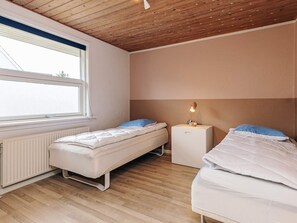 Une chambre avec deux lits simples, une table de chevet avec une lampe, une fenêtre et un radiateur.