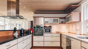 Een moderne keuken met een stenen vloertegel, inbouwapparatuur en witte keukenkastjes.