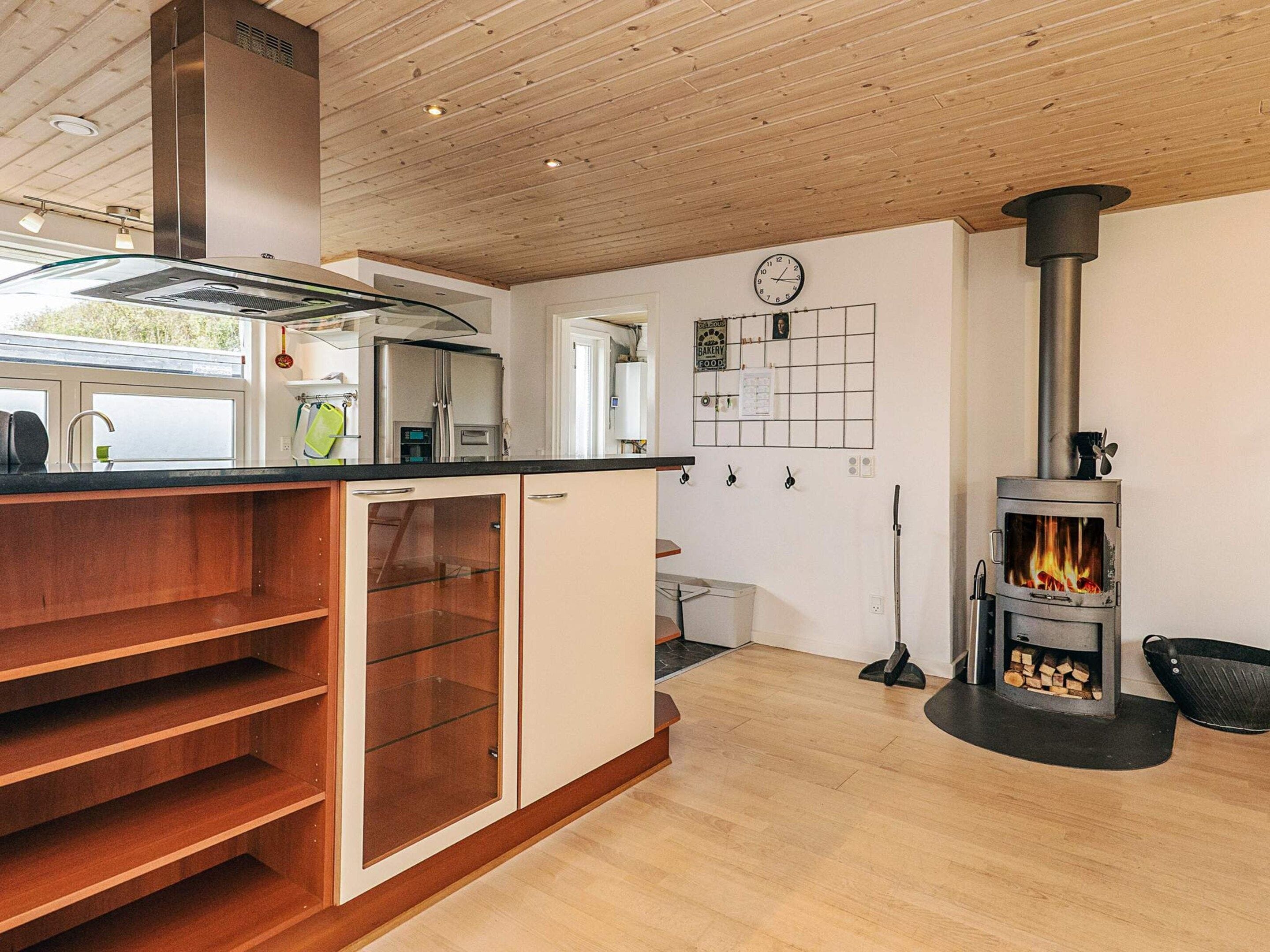 Eine moderne Küche mit Einbauherd, Holzschränken und einem Fenster mit Blick auf einen Garten.