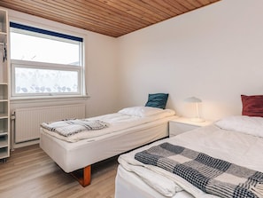 A bedroom with two single beds, a window with a view, a radiator, and a shelf unit. - 9 Person Holiday Home in Skagen (Skagen)