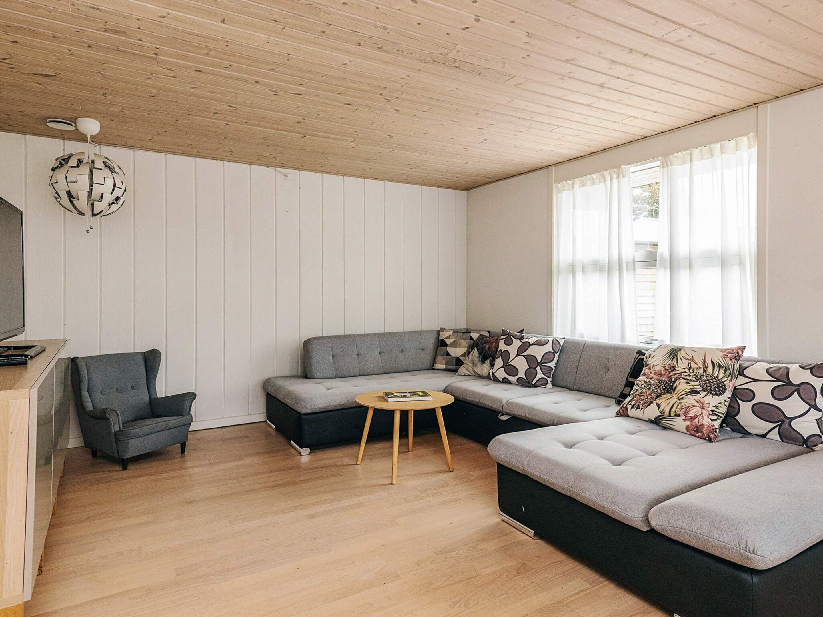 A modern living room with a sectional sofa, a small round table, and a single armchair.