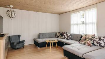 A modern living room with a sectional sofa, a small round table, and a single armchair.