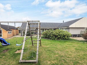 A backyard with a wooden swing set, a rope ladder, and a slide. - 9 Person Holiday Home in Skagen (Skagen)