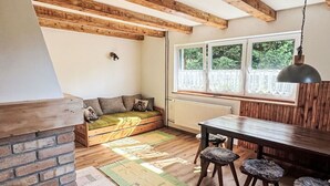 A rustic kitchen with exposed wooden beams, a brick fireplace, a dining area with a table and chairs, and a window with a view of greenery. - Stunning private villa for 7 people with WIFI, TV and pets allowed (Chodov)