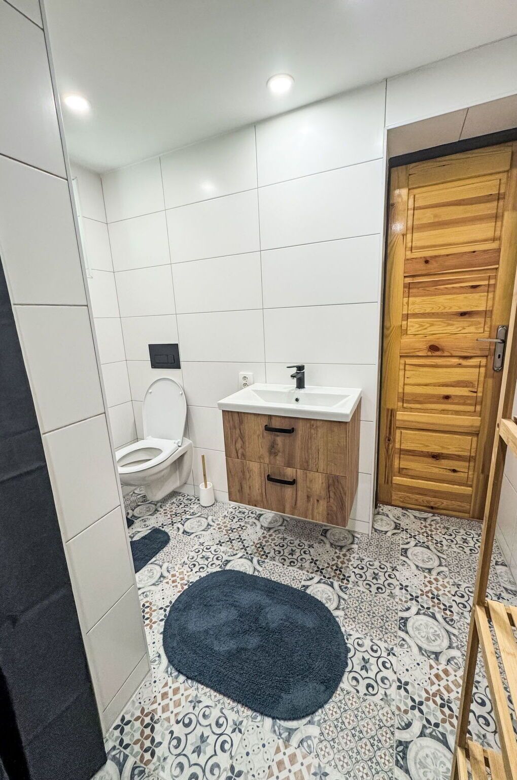 Un baño con inodoro, lavamanos y puerta de madera.