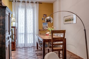 Ein Essbereich mit einem Holztisch, Stühlen, einer Lampe und einem Vorhang.