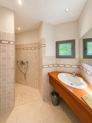 Une salle de bain avec une douche, un lavabo et une fenêtre.
