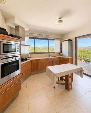 Una cocina con horno empotrado, un lavabo y una mesa con mantel.