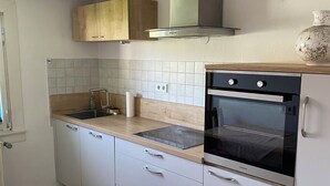 Moderni keittiö, jossa on sisäänrakennettu uuni, pesuallas ja puukaapit.